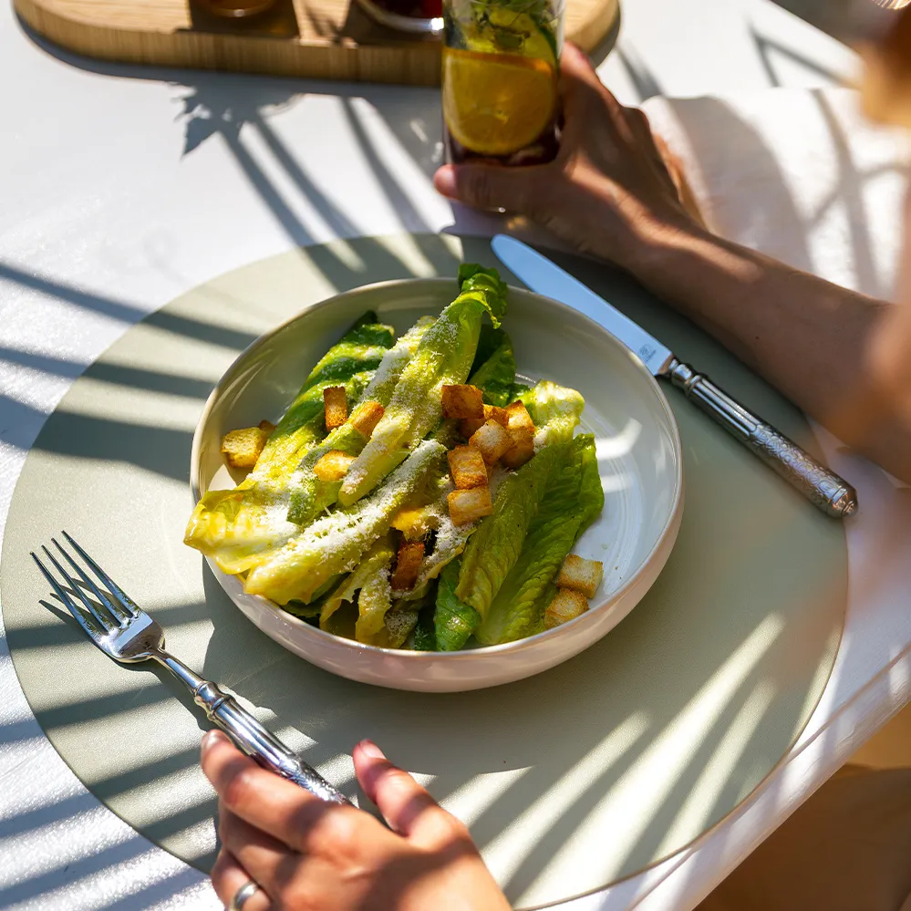 Salată Caesar cu frunze de salată, crutoane și parmezan, servită pe farfurie